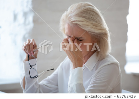 Tired middle-aged woman suffer from headache in office Tired middle-aged woman suffer from headache in office 65762429