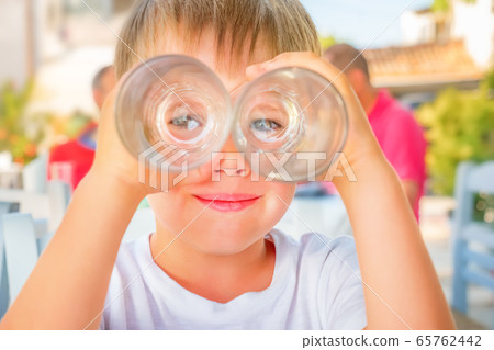 Funny kid looking through two drink glasses as if 65762442