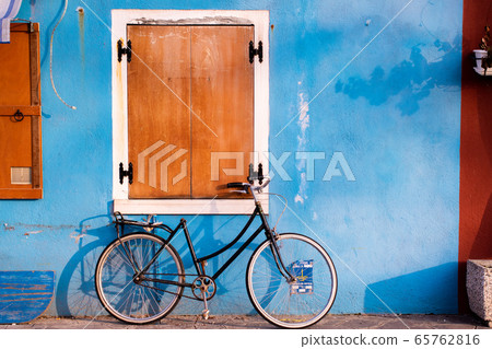 A bicycle with a good atmosphere to snuggle up to a private house with a blue wall 65762816