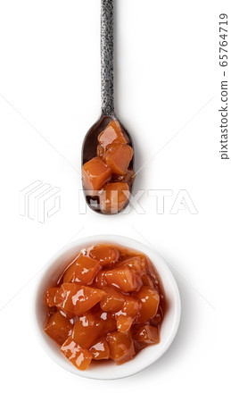 Small glass bowl and spoon of apricot jam 65764719