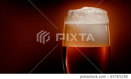 Lager beer settles in the glass with a white cap 65765290