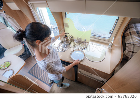 Woman cooking in camper, motorhome interior 65765326