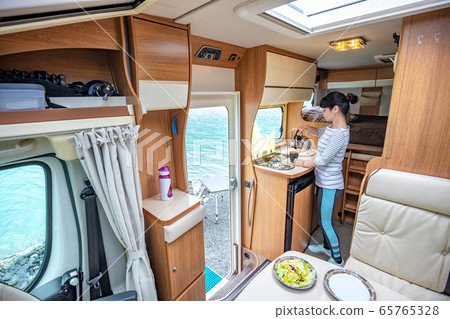 Woman cooking in camper, motorhome interior 65765328