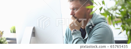 Man sits front computer monitor looking for info 65765435