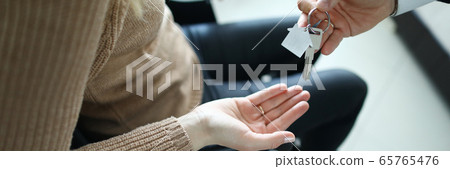 Male businessman hand passes the key to a woman from new housing Male businessman hand passes the key to a woman from new housing 65765476