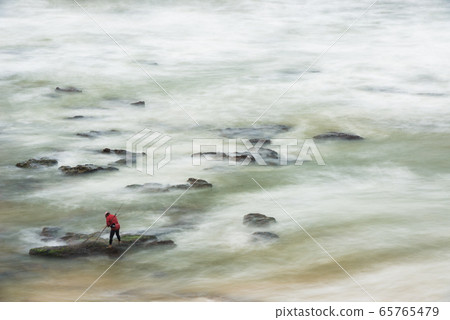 Long exposure photograph of a shellfisherman working on the rocks at Seixo beach, Torres Vedras Long exposure photograph of a shellfisherman working on the rocks at Seixo beach, Torres Vedras 65765479
