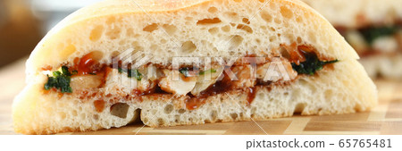 Cut chiken sandwich with ketchup against kitchen background Cut chiken sandwich with ketchup against kitchen background 65765481