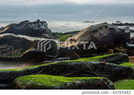 Long exposure photography of sea waves and mist on the rocks of the shore of Porto Novo Long exposure photography of sea waves and mist on the rocks of the shore of Porto Novo 65765482