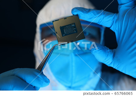 Man in uniform holds microprocessor with forceps 65766065
