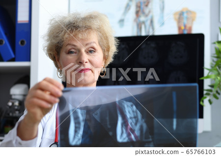 Experienced doctor woman looking at x-ray office Experienced doctor woman looking at x-ray office 65766103