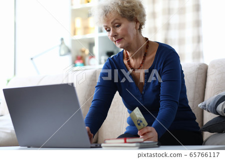 Grandmother sits sofa in laptop with credit card 65766117