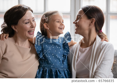 Smiling three generations of women relax on couch together 65766835