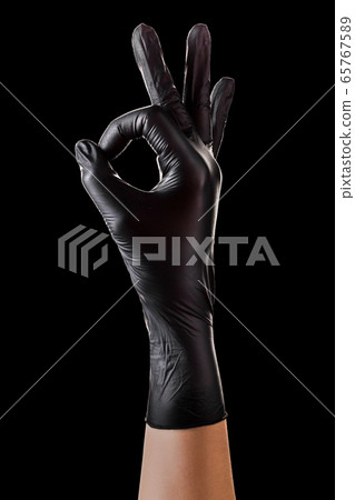 Hand in black gloves holding something with two Hand in black gloves holding something with two 65767589