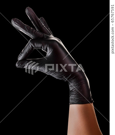 Hand in black gloves holding something with two Hand in black gloves holding something with two 65767591
