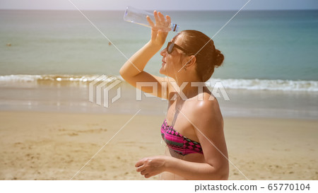 woman pours water on head refreshing against exotic nature woman pours water on head refreshing against exotic nature 65770104