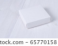 White box on wooden white table. Stock photo. White box mockup for product and advertising with cover on white wooden background. Side view. Delivery service concept. Blank package for your design 65770158