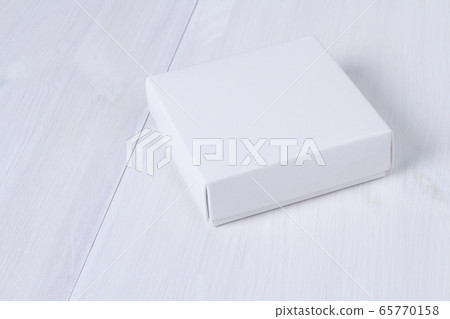 White box on wooden white table. Stock photo. White box mockup for product and advertising with cover on white wooden background. Side view. Delivery service concept. Blank package for your design 65770158