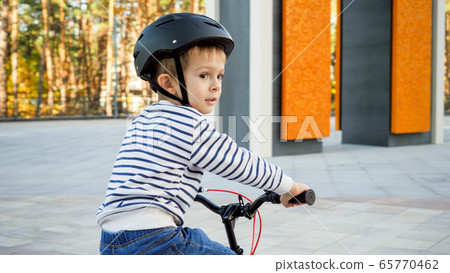 Portrait of little toddler boy weraing protective helmet riding his bicycle 65770462