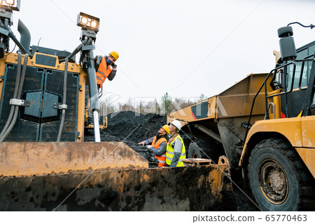 Heavy machinery and workers in pit of quarry 65770463