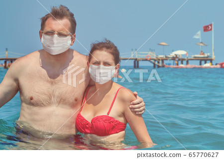 Two people in surgical masks in water of sea. 65770627