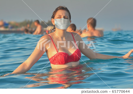 Swimming in medical mask during covid-19. 65770644