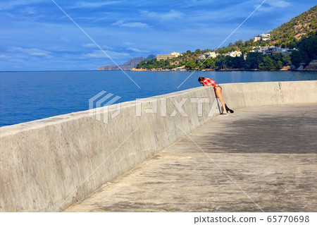 A lady in a beach suit watches the sea fish 65770698