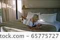 Cute woman on bed happy and excited to hear from her friend while on vacation 65775727