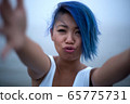 Woman in white dress and funky blue hair grabs cameraman for a kiss 65775731
