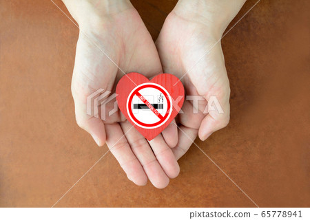 Hand of person holding heart object with non-smoking sticker Hand of person holding heart object with non-smoking sticker 65778941