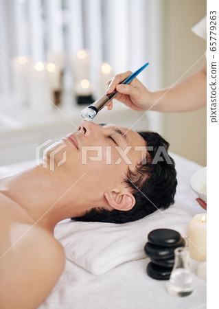 Beautician applying clay mask 65779263