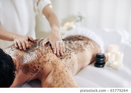 Cosmetologist applying coffee peeling Cosmetologist applying coffee peeling 65779264