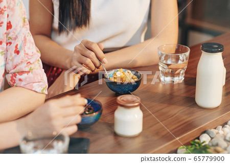 Women having cornflakes and yogurt 65779900