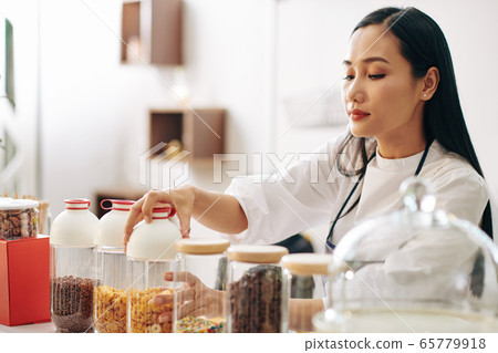 Waitress opening container with cornflakes 65779918