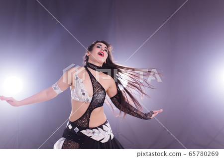 Young woman belly dancer in exotic dress with gold, dancing tribal fusion dance in studio. 65780269