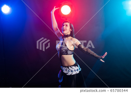 Young woman dancing in Tribal Fusion style. Belly dance on the stage. 65780344