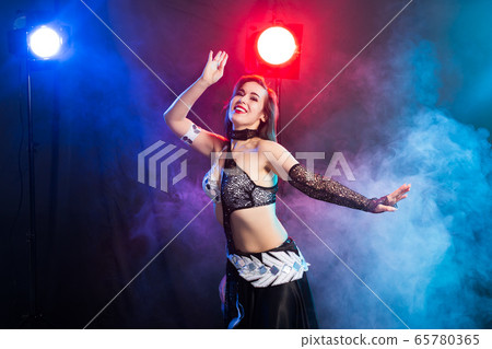 Young woman belly dancer in exotic dress with gold, dancing tribal fusion dance in studio. Young woman belly dancer in exotic dress with gold, dancing tribal fusion dance in studio. 65780365