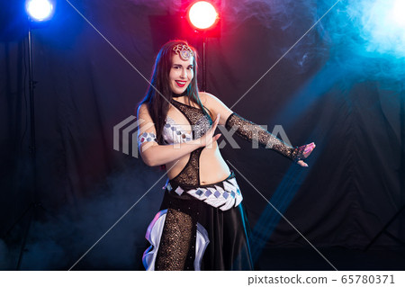 Young woman dancing in Tribal Fusion style. Belly dance on the stage. 65780371