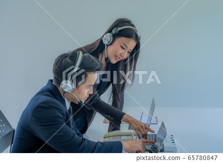 How can I help you? Beautiful call center employees in headphones are working at modern offices, focusing on woman. 65780847