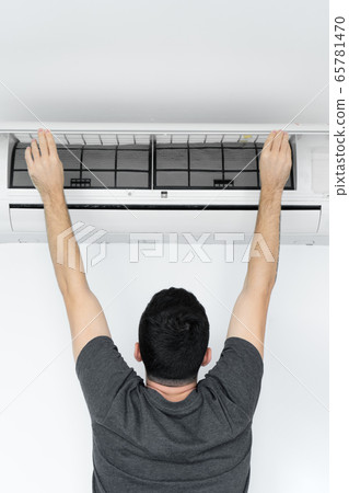 The guy cleans the filter of the home air The guy cleans the filter of the home air 65781470