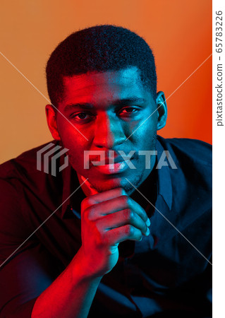 Face African American stylish man posing on the blue and red neon light background. Face African American stylish man posing on the blue and red neon light background. 65783226