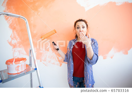 Funny woman painting wall. Renovation, redecoration and repair concept. 65783316