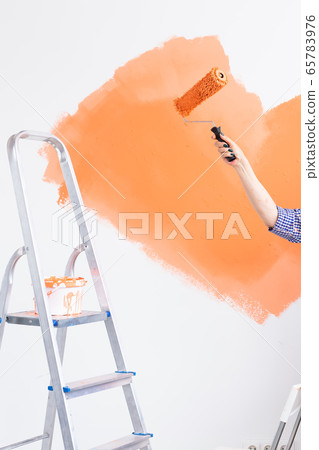 Close-up of middle-aged woman painting wall in her new apartment. Renovation, redecoration and repair concept. Close-up of middle-aged woman painting wall in her new apartment. Renovation, redecoration and repair concept. 65783976