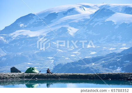 Man hiker resting by camp tent in mountains. Man hiker resting by camp tent in mountains. 65788352