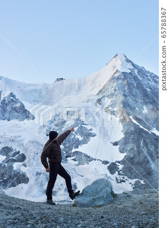 A tourist pointing on one of the most beautiful mountains in Swiss Alps - Ober Gabelhorn 65788367