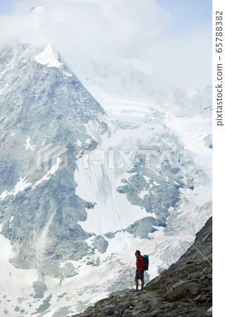 Male tourist climbing snowy rocky cliffs of beautiful Penning Alps in Switzerland Male tourist climbing snowy rocky cliffs of beautiful Penning Alps in Switzerland 65788382