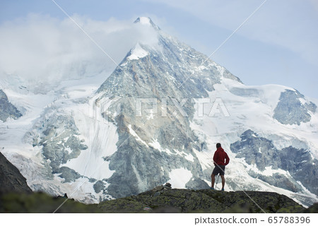 Male tourist climbing snowy rocky cliffs of beautiful Penning Alps in Switzerland Male tourist climbing snowy rocky cliffs of beautiful Penning Alps in Switzerland 65788396