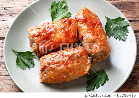Cabbage rolls with beef, rice and vegetables on the plate. Stuffed cabbage leaves with meat. Wooden background. Cabbage rolls with beef, rice and vegetables on the plate. Stuffed cabbage leaves with meat. Wooden background. 65789410