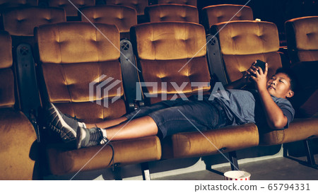 A boy laying down and playing mobile phone A boy laying down and playing mobile phone 65794331