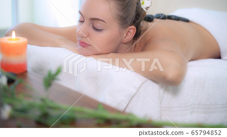 Hot stone massage treatment by therapist in spa. Hot stone massage treatment by therapist in spa. 65794852