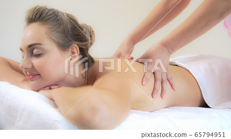 Woman gets back massage spa by massage therapist. 65794951